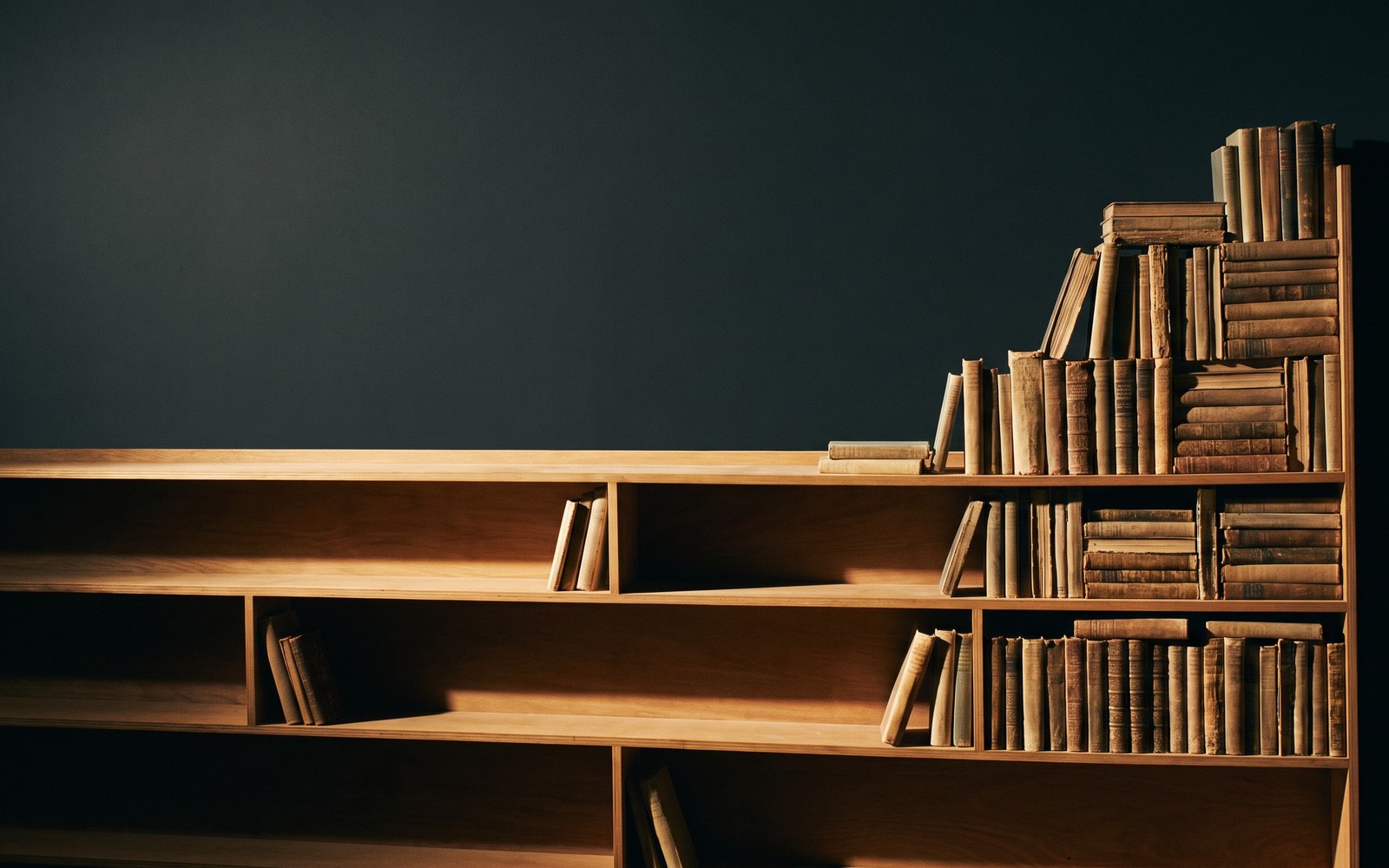 A bar chart histogram rendered as a physical bookshelf, most shelves nearly empty except a dense, tightly packed cluster of books at one end