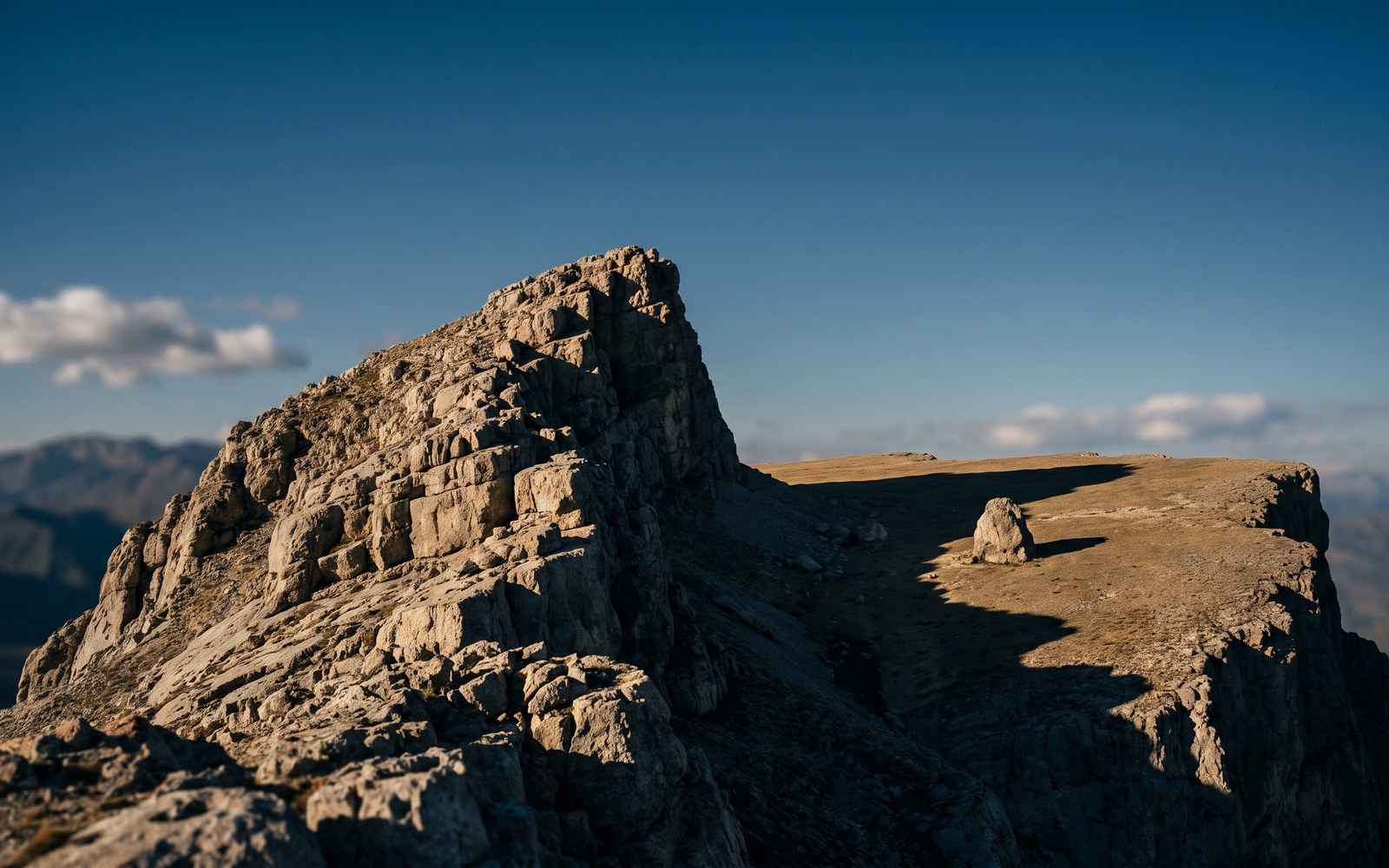 A steep rocky slope that suddenly levels into a flat stable plateau under an open sky