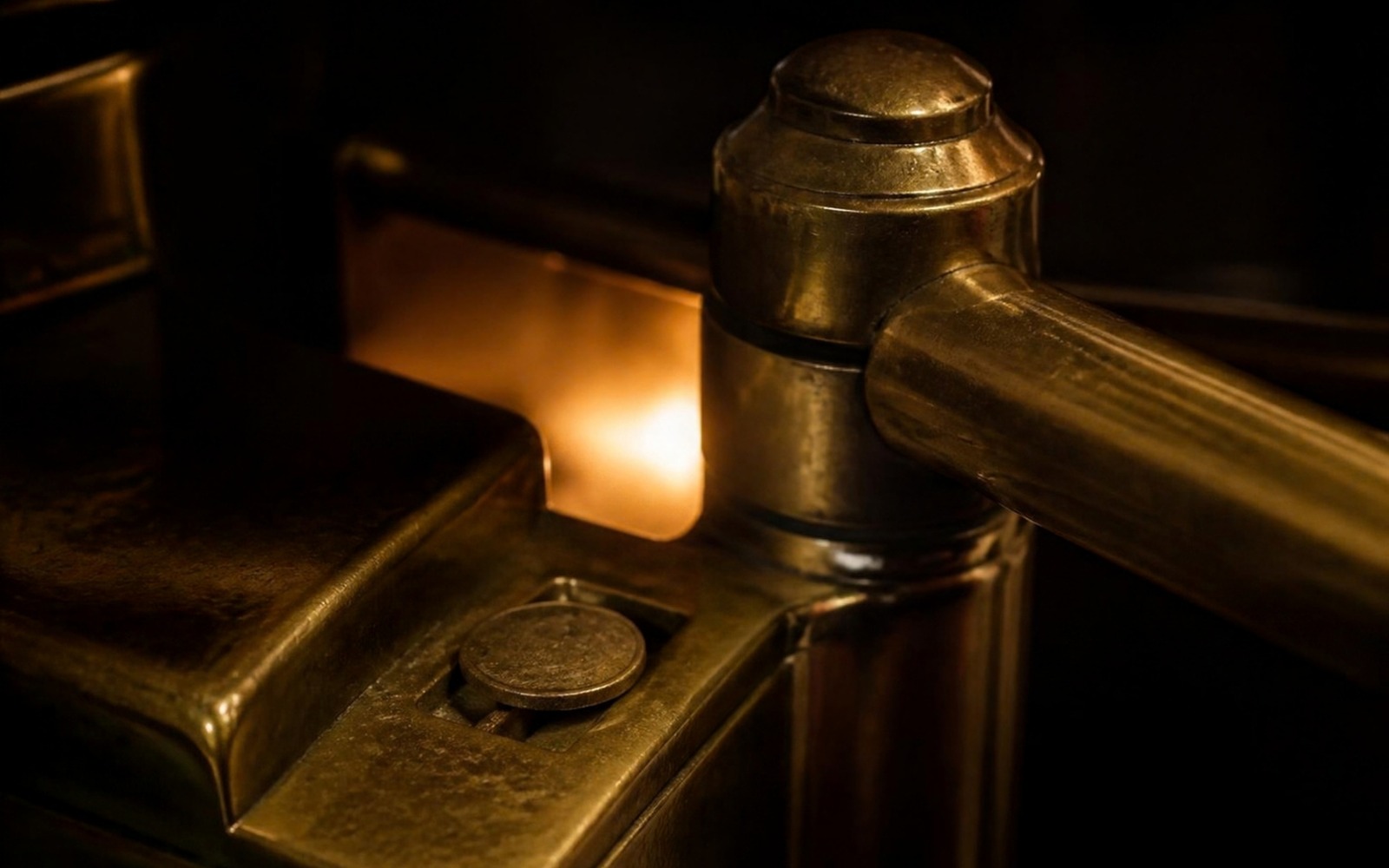 Macro photograph of a vintage brass turnstile or tollgate mechanism glowing with warm amber light in a dark room