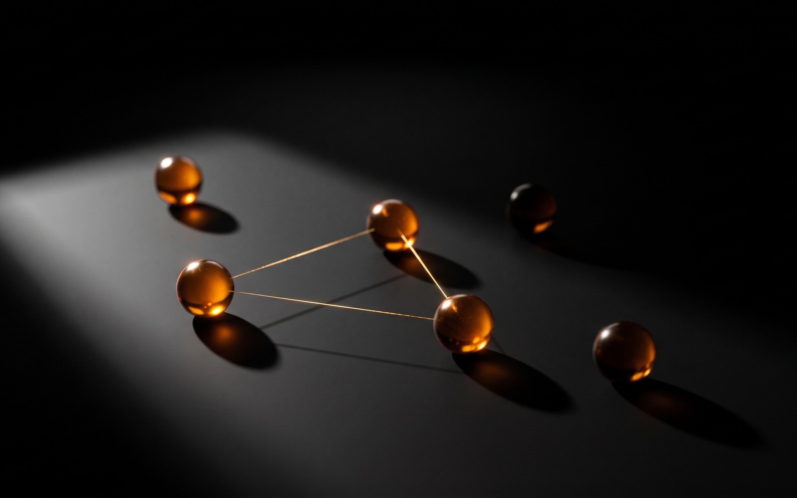 Five glowing amber orbs on a dark surface, three connected by thin gold threads in a quorum, two sitting isolated and unconnected