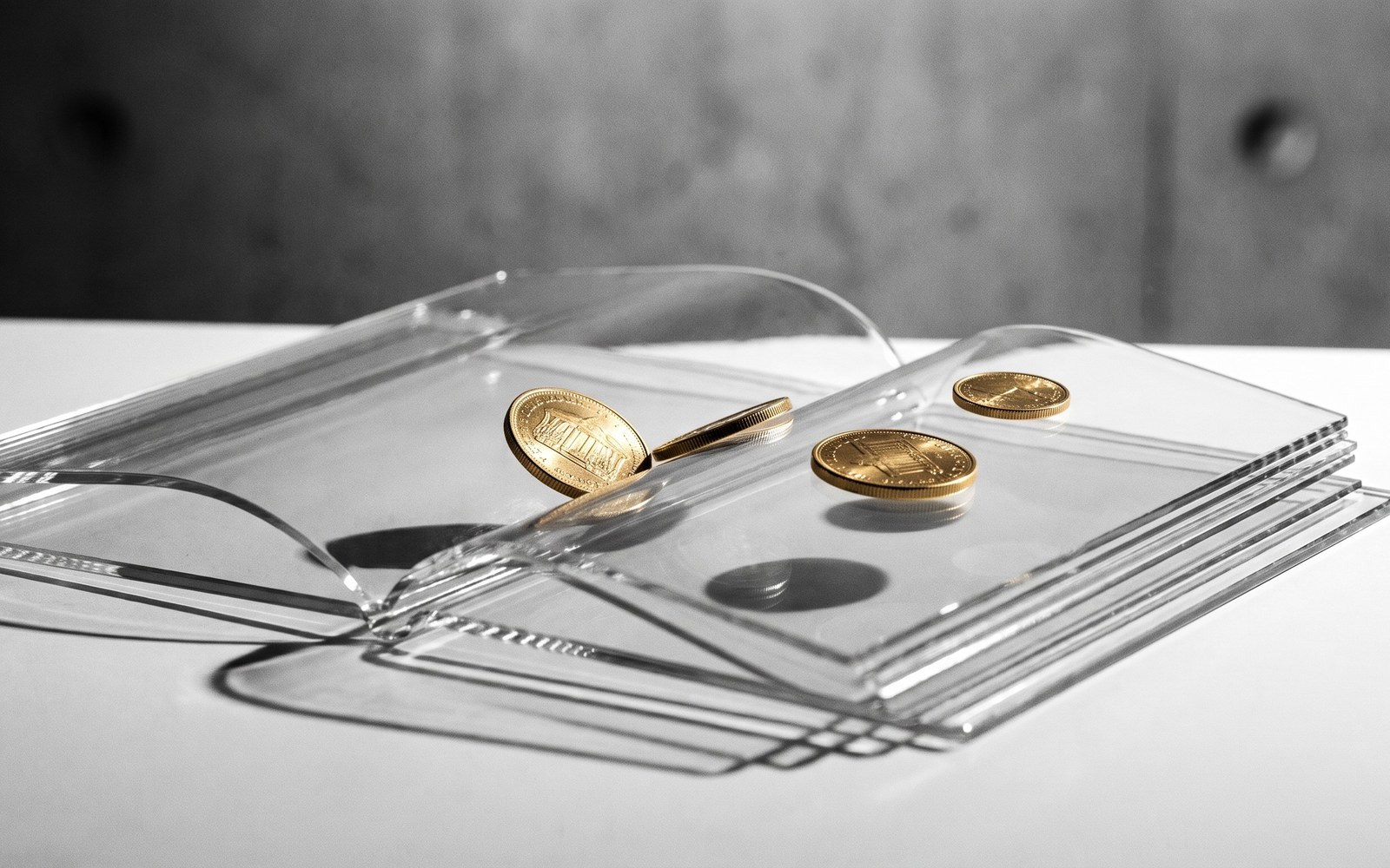 A see-through glass ledger book with only a few precisely placed coins on its pages instead of being filled to the brim