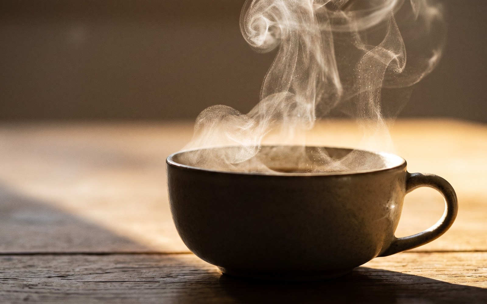 A wisp of steam rising from a fresh cup of coffee in warm morning light