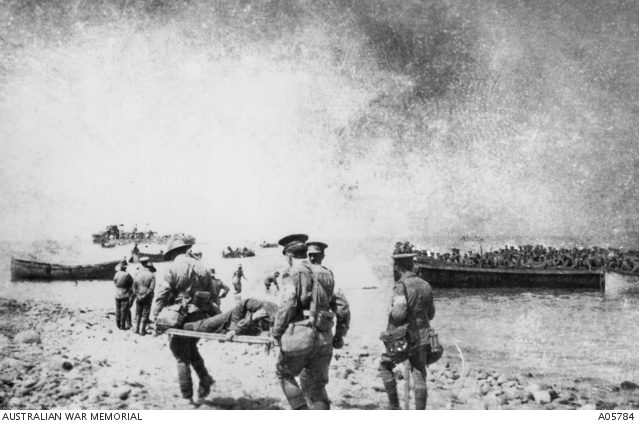Stretcher bearers carrying a wounded soldier to barges loaded with other wounded men, Anzac Beach, Gallipoli, 1915.