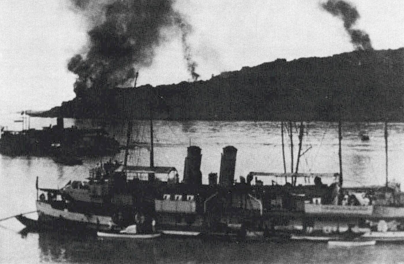 A black-and-white photograph of the American gunboat USS Tutuila moored on the riverfront at Chongqing, China, during a Japanese bombing raid on the city, circa 1938.
